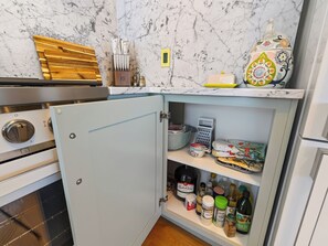 A kitchen with a marble backsplash, a built-in oven, and a cabinet with various food items and kitchenware. - Historic Manor w/ Hidden Speakeasy, 3BR/2.5BA (Heber City)