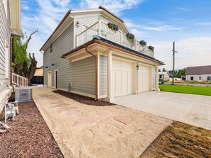 A two-story house with a garage, a covered porch, and a small garden area. - Swanky Mid Century Gem, 2BR/1BA, Deck, Fireplace (Heber City)