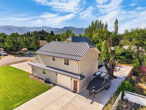 Une maison à deux étages avec un garage, un patio couvert et une vue sur les montagnes en toile de fond.