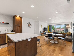 Een moderne keuken met een centraal eiland, houten kastjes en een witte spatwand.