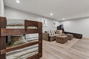 A modern bedroom with a bunk bed, a sofa, and a staircase. - New Bethel Retreat | Hot Tub, Pinball & Fireplace (Bethel)