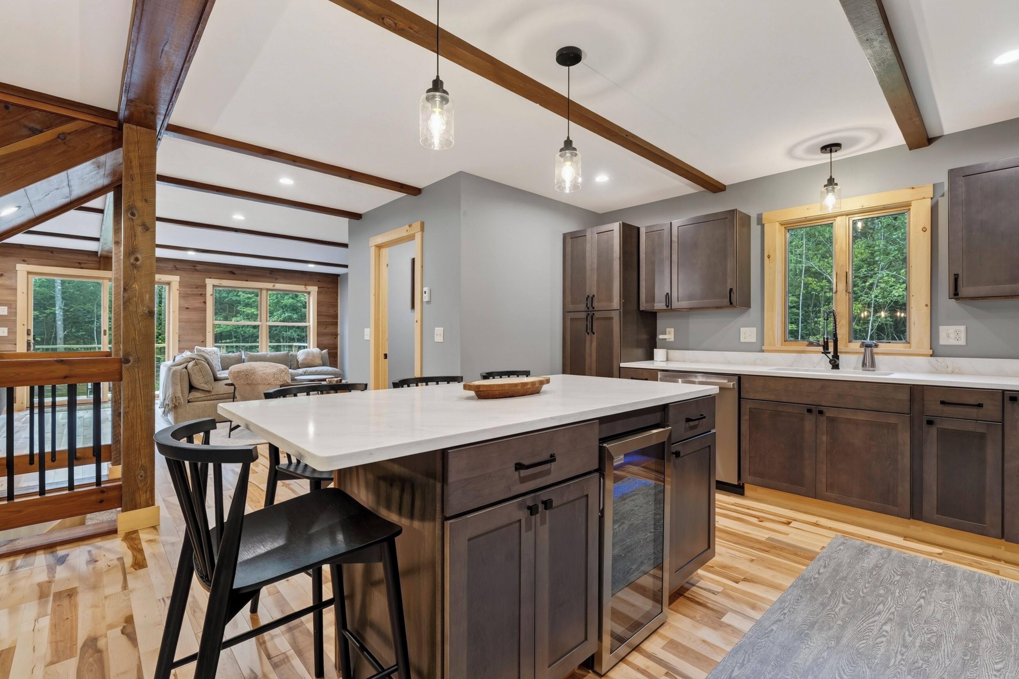 Une cuisine moderne avec un îlot central, des meubles de cuisine en bois foncé et une grande fenêtre.