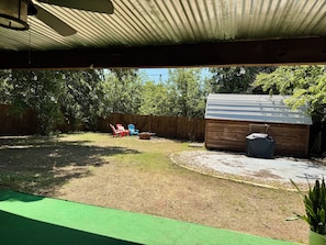 A backyard with a wooden shed, a green artificial turf area, and a wooden fence.