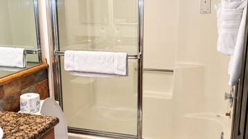 Een badkamer met een douchecabine van glas, een toilet, een wastafel met een marmeren blad en een handdoekhouder.