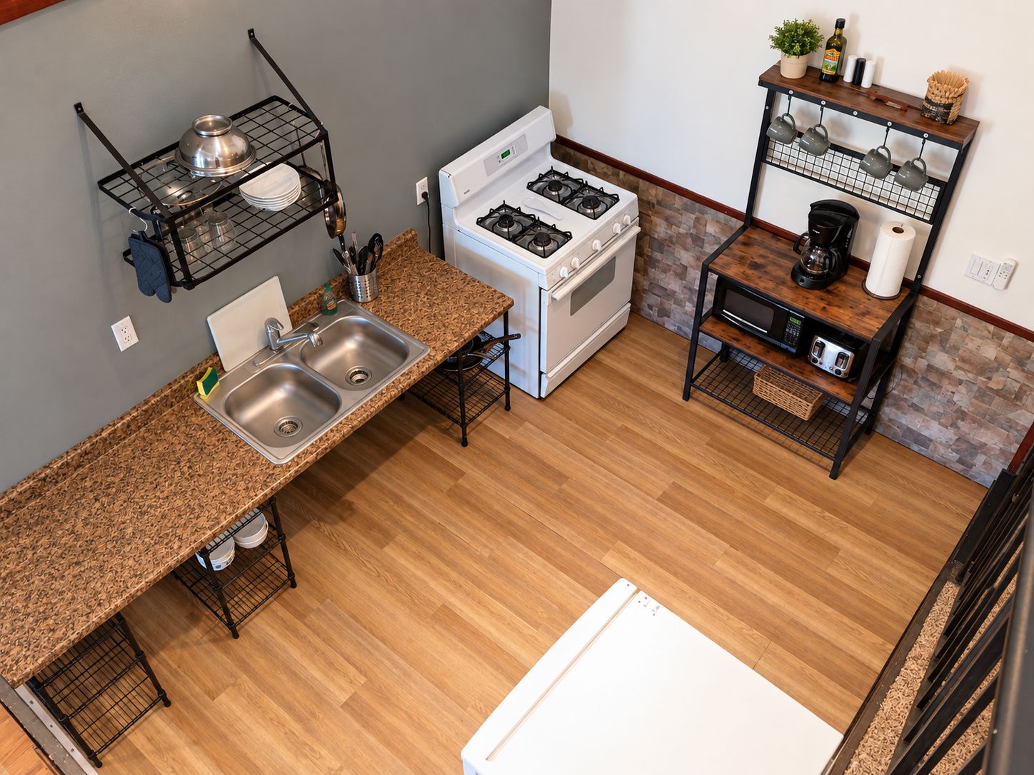 A compact kitchen with a stove, sink, and a coffee machine.