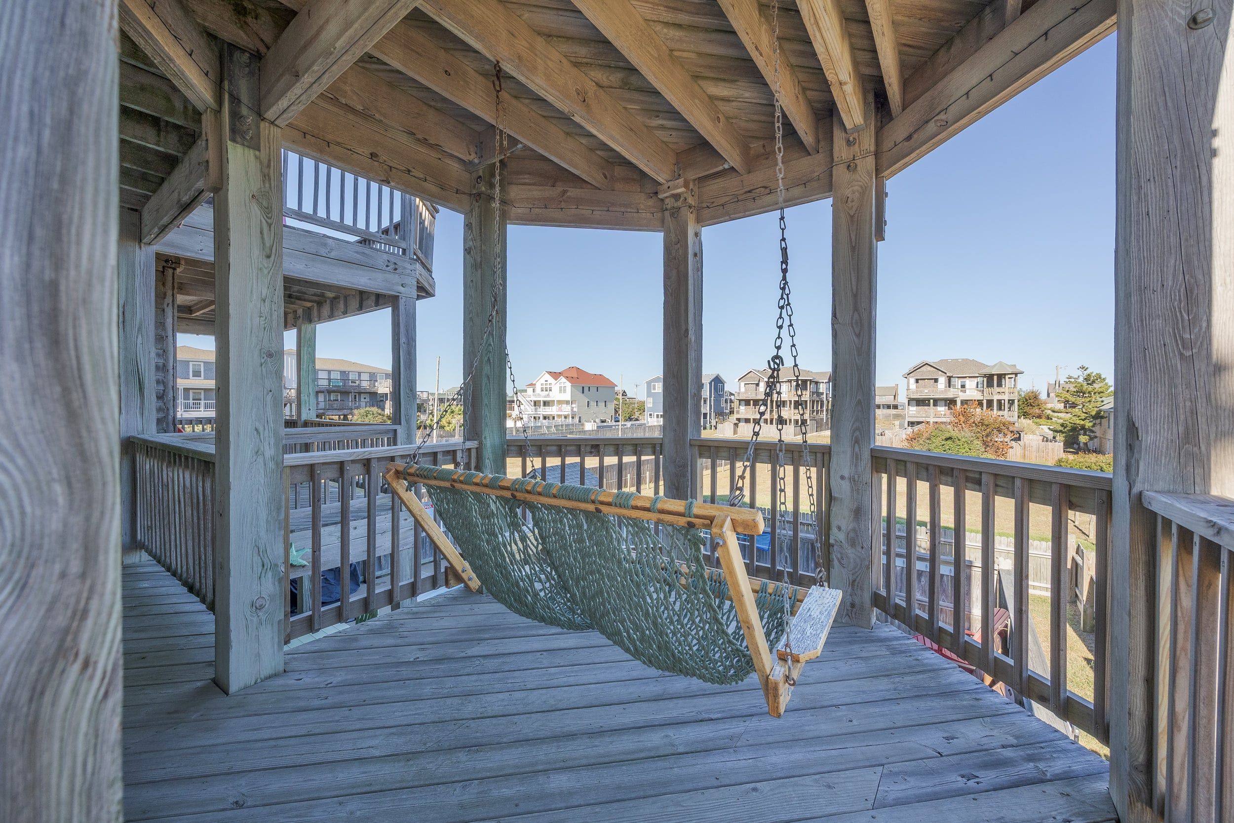 A wooden deck with a hammock and a view of residential buildings.