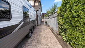 Un estrecho sendero que lleva a una propiedad residencial, con una caravana estacionada a la izquierda.