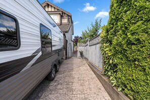 Ein schmaler Weg führt zu einem Wohnhaus, links steht ein Wohnwagen.