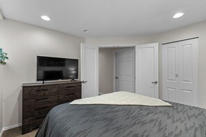 Ein Schlafzimmer mit Bett, Schminktisch, Fernseher und einer Tür.