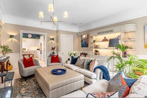 Ein geräumiges Wohnzimmer mit Sofa, Hocker und einem Essbereich mit Tisch und Stühlen.