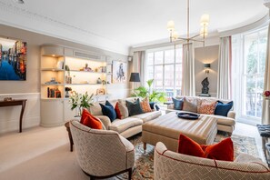 Ein geräumiges Wohnzimmer mit einer Sofagarnitur, einem Couchtisch und einem Bücherregal.