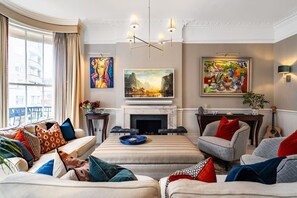 Ein Wohnzimmer mit einer Couch, Sesseln, einem Kamin und Kunstwerken an den Wänden.