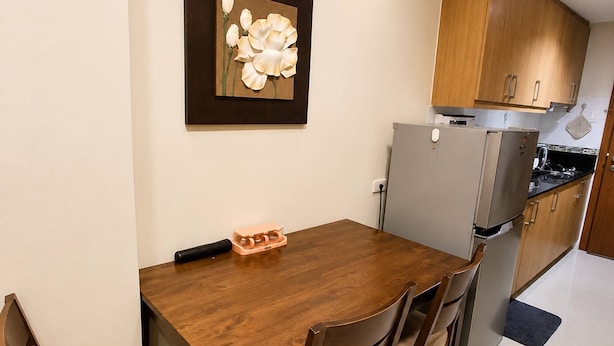 Un coin repas avec une table et des chaises en bois, un réfrigérateur et des placards en bois.