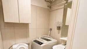 Une petite salle de bain comprenant des toilettes, un lave-linge et un lavabo.