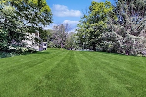 A well-maintained lawn with a small building, surrounded by trees and a clear sky. - Four Season Condo: seasonal pool, ski, hike & golf (Warren)