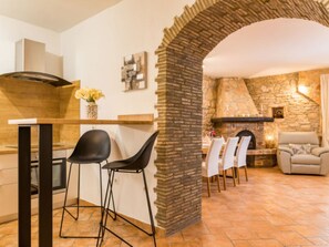 A modern kitchen with a stone archway leading to a dining area with a fireplace. - Villa Dominique by Interhome (Svetvinčenat)