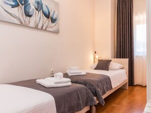 Ein Hotelzimmer mit zwei Betten, einem Bild an der Wand und einem Fenster mit Vorhängen.