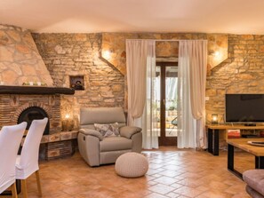 A stone-walled room with a fireplace, a sofa, a television, and a window with curtains. - Villa Dominique by Interhome (Svetvinčenat)