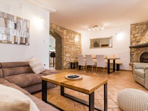 Ein Wohnzimmer mit Steinwand, Kamin, Essbereich mit Stühlen und einer Couch.