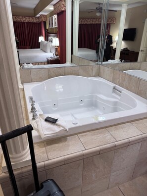 A hotel bathroom with a large bathtub, a mirror, and a bed in the background. - Resort Spa and Villa with 5 bedrooms  in Orlando fully furnished vacation rental (Orlando)