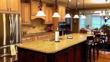 A kitchen with a central island, stainless steel appliances, and pendant lighting.