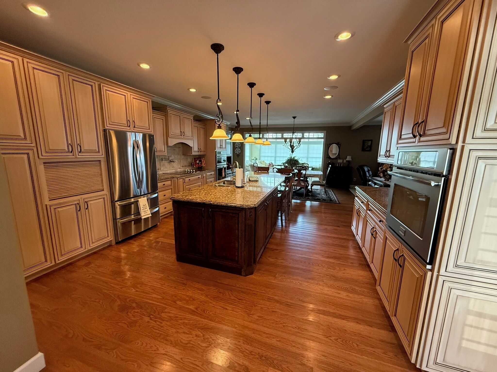 A spacious kitchen with a central island, stainless steel appliances, and wooden cabinetry.