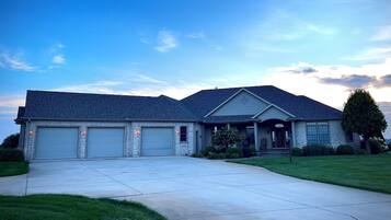 A two-story house with a garage, a covered porch, and a well-maintained lawn.