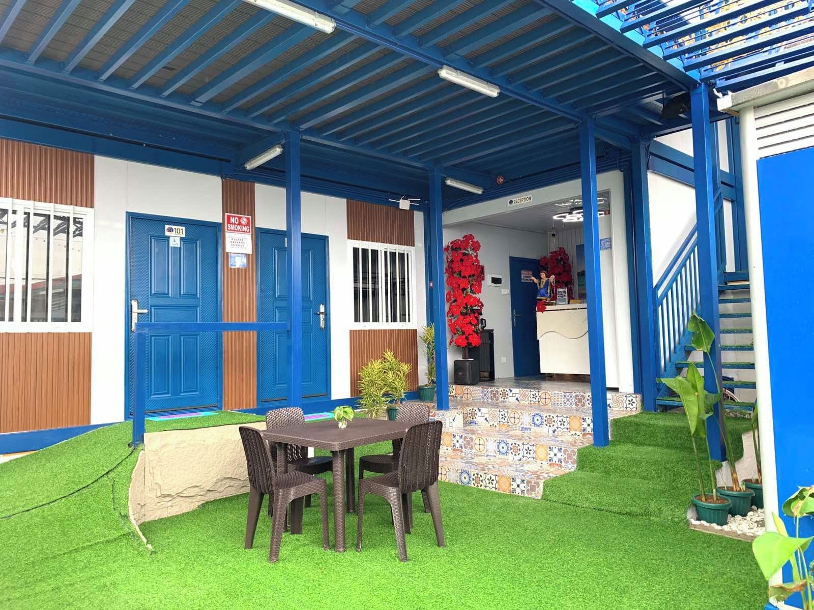 A covered outdoor area with a reception desk, a blue door, and artificial grass.