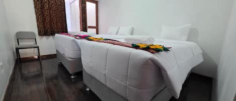 A hotel room with a double bed, a chair, and a window with curtains.