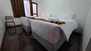 A double bed with a white duvet and a colorful blanket, a grey chair, and a window with curtains. - Cusco Inka Sky (Cusco)