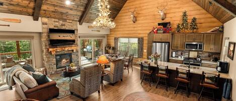 A spacious living area with a fireplace, a dining table, and a kitchen with wooden cabinets and a stainless steel refrigerator.