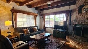 A cozy living room with a fireplace, wooden ceiling, and a patterned rug. - Live in a historic castle near U of A in sunny Tucson (Tucson)