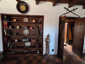 A room with a wooden bookshelf filled with various items, a wall clock, and a statue. - Live in a historic castle near U of A in sunny Tucson (Tucson)