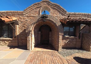 A brick building with an arched entrance, a tiled roof, and a lantern above the door. - Live in a historic castle near U of A in sunny Tucson (Tucson)