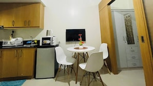 A compact kitchen with a refrigerator, microwave, and a small dining table with chairs. - Charming 1-bedroom Apartment Near Mall of Asia (Pasay)