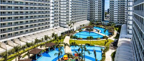 A high-rise hotel with multiple balconies, a central swimming pool, and a children's play area.