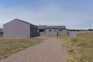 Un bâtiment moderne avec une allée de gravier menant à une entrée fermée par un portail.