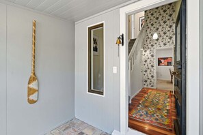 Ein Korridor mit einem Holzschläger an der Wand, einer Tür mit Spiegel und einem gemusterten Teppich, der zu einer Treppe führt.
