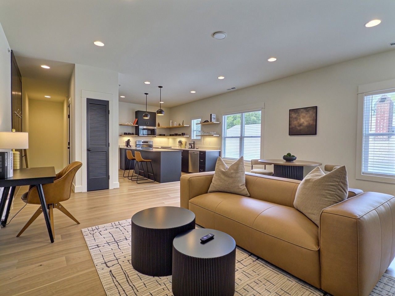 A modern living room with a sofa, coffee table, and a dining area with chairs.