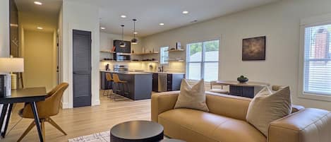 A modern living room with a sofa, coffee table, and a dining area with chairs.