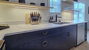 A modern kitchen with a marble countertop, built-in knife block, and a large island with drawers. - Upscale Stay, Free Parking, Walk to Eats and Parks (Birmingham)