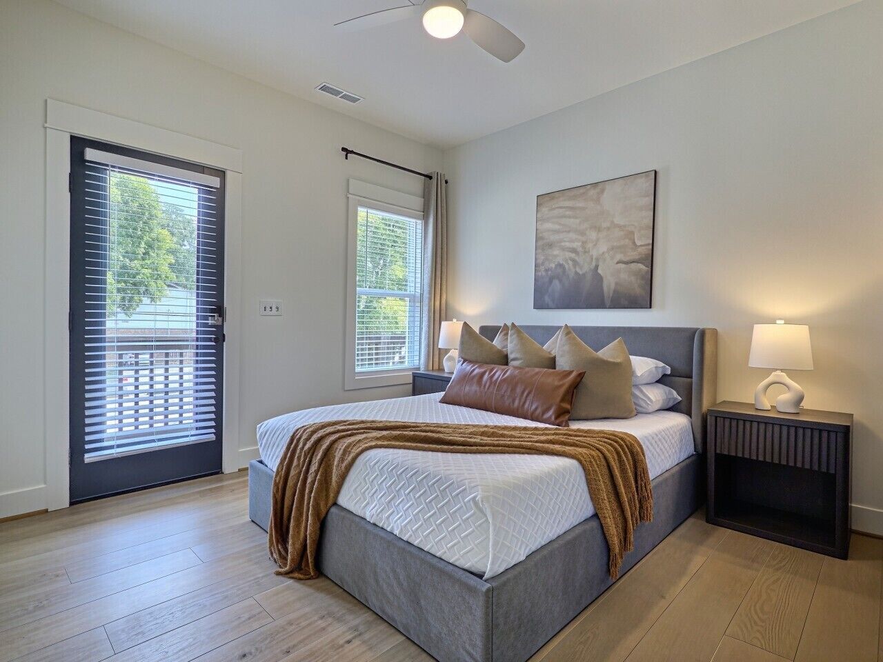 A bedroom with a bed, bedside tables, a ceiling fan, and a window with blinds.