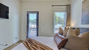 A bedroom with a bed, a TV mounted on the wall, and a window with blinds. - Upscale Stay, Free Parking, Walk to Eats and Parks (Birmingham)