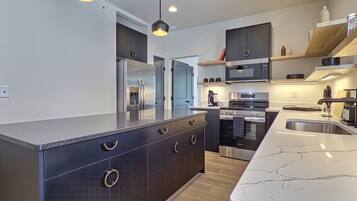 A modern kitchen with a central island, built-in appliances, and pendant lighting.