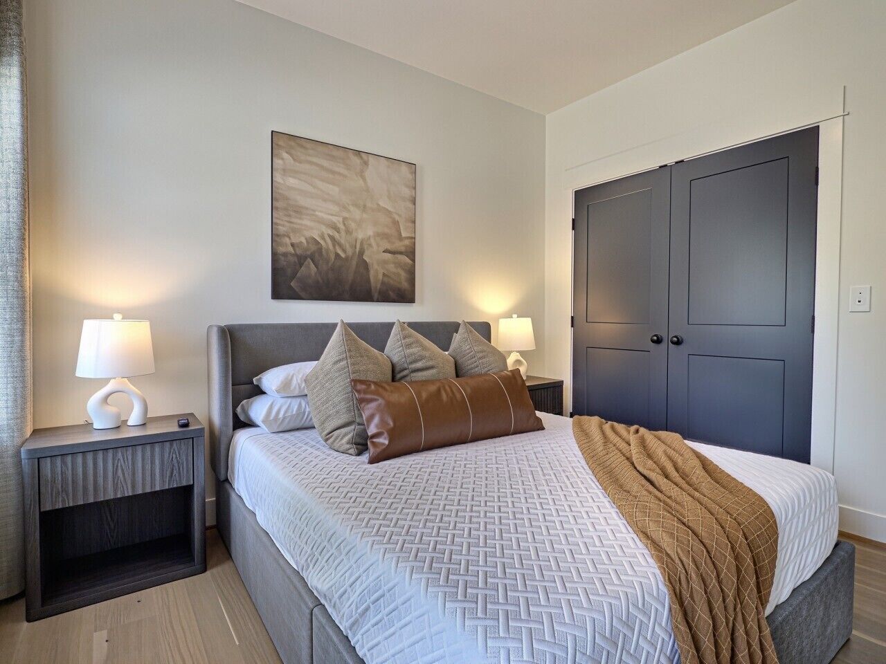 A bedroom with a bed, nightstands, a wardrobe, and a painting on the wall.