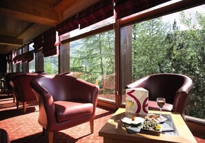 A dining area with leather chairs, a table with a menu, and a scenic view through large windows.