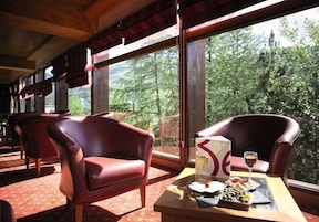 Un comedor con sillas de cuero, una mesa con un menú y una vista panorámica a través de amplios ventanales.