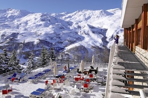 A snow-covered mountain view with a balcony overlooking a ski slope.