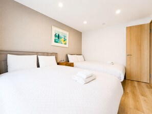 Een hotelkamer met twee bedden, een houten deur en een schilderij aan de muur.