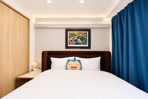 A hotel room with a bed, a framed picture on the wall, a nightstand with a lamp, and a blue curtain. - SERENE | Nishikujo, 4th Floor | 60 ㎡, Sleeps 7 | Direct Access to USJ and Osaka Station (大阪市)